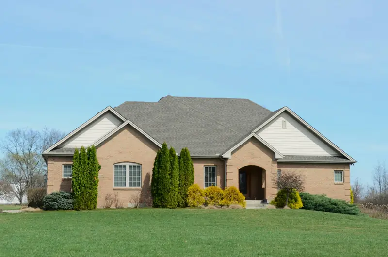 Single-story brick ranch house with a hip roof and wide green lawn, typical of East Texas suburbs