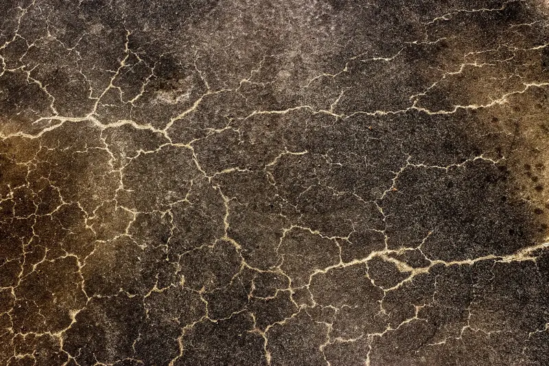 Close view of a cracked concrete floor slab with spreading hairline cracks
