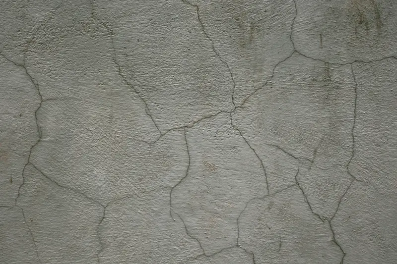 Close-up of a network of cracks across a concrete wall surface