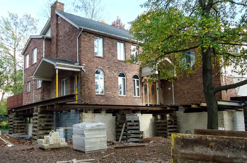 Older house raised on steel beams and cribbing while its foundation is rebuilt
